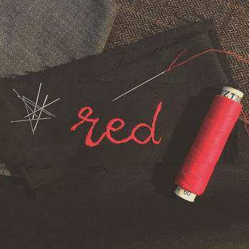Hand stitched the word Red with red garn on some black fabric