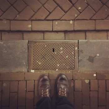 Brown leather boots, standing next to a gutter marked by Amsterdams three X's