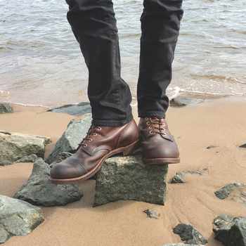 Brown leather boots, standing on a rock at a beach